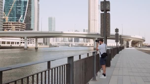 在迪拜的Al Manara塔附近 一个男人把镜头集中在他的相机上 为摩天大楼拍照 — 图库视频影像