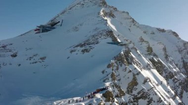Karlı bir dağın kenarında yürüyen yürüyüşçülerin insansız hava aracı görüntüleri..