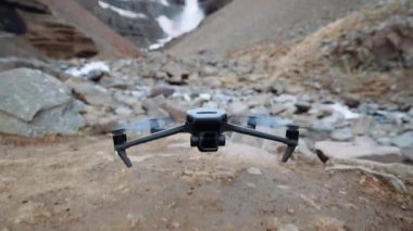 İnsansız hava aracının yakın çekim görüntüsü kayalık bir dağın eteğinde yavaşça yerden yükseliyor..
