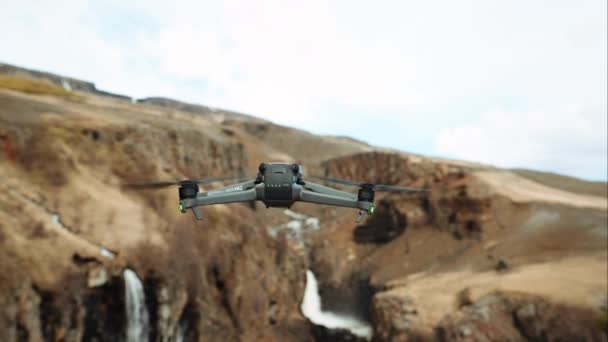 无人机的特写镜头 它从摄像机前飞走 清晰地看到周围的群山和瀑布 — 图库视频影像
