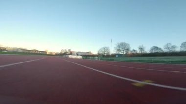 Gün batımında engellerin altından ve üstünden geçen buzlu bir pistte alçaktan uçan bir dronun hızlı hareketi