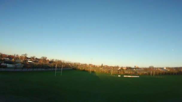 日落时 无人驾驶飞机在橄榄球场的栅栏和结构中飞得又快又低 — 图库视频影像