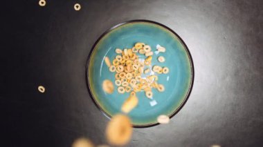 Yuvarlak mısır gevreğinin boş bir kaseye dökülürken hafifçe döküldüğünü gösteren bir üst görüntü.