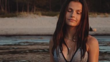 Genç bir bayanın kameraya neşeyle deniz suyu attığı orta ölçekli bir fotoğraf.