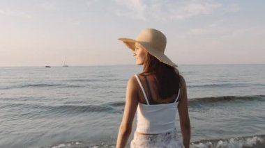 Denizde güneşe bakan bir kızın orta boy fotoğrafı.