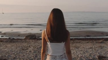 Deniz kenarında fotoğraf çeken genç bir kızın arka görüntüsü.