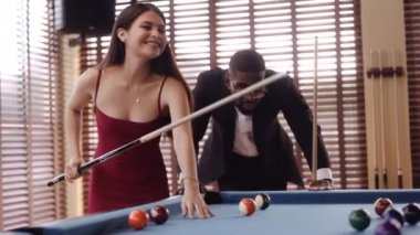 Bilardo oynarken gülümseyen kadına bakan bir adamın videosu.