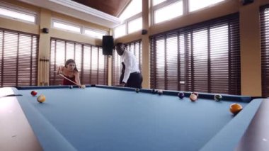 Bilardo masasının köşesinde bir kadının bilardo topuna ateş ettiğini gösteren bir video.