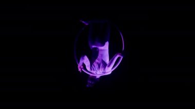 Mor spot ışıklarıyla arka planda ters Scarab pozu veren bir kadının tam pozu.