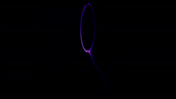 在黑暗的背景中 一个女人用紫色的聚光灯聚焦在她身上 双手握住天线圈的中景照片 — 图库视频影像