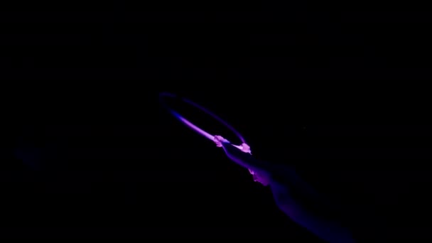 紫色のスポットライトが彼女に焦点を当てて暗い背景に空の輪のバーの下に分割女性の傾斜ローアングルショット — ストック動画