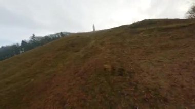 Alçaktan uçan bir dron, deniz kenarındaki çimenli yamaçlara dönmeden önce insanlarla birlikte Himmelbjerget kulesine yaklaşıyor.