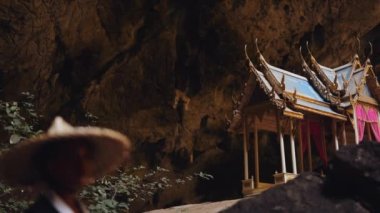 Kuha Karuhas köşkü ve kimono ve bambu şapkalı bir kadın. Phraya Nakhon mağarasında büyük kayaların yanında yürüyor.