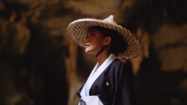 Kuha Karuhas Pavyonu 'nun önünde eğilip mağaranın kayalık duvarlarına bakan bir kadının kavisli görüntüsü.