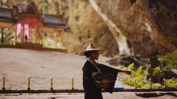 一个穿着和服 头戴竹帽 手握扇子 袖子紧贴着模糊的库哈 卡鲁哈亭子的妇女的中景照片 — 图库视频影像