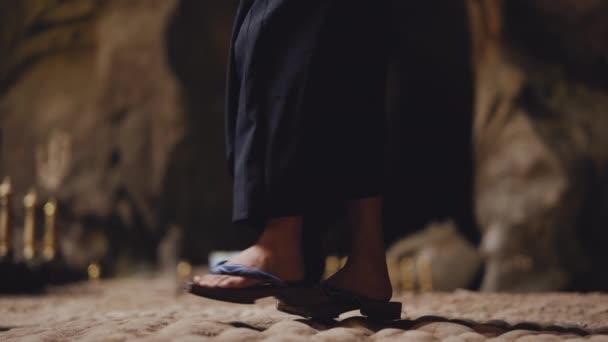 洞窟の岩の地面に伝統的な木製のサンダルで二歩前進する女性の足のクローズアップショット — ストック動画