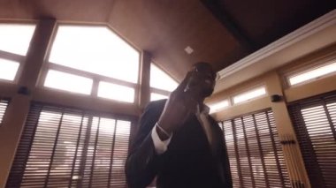 Bir adam kameraya doğru barış işareti yaparken elini sallıyor.