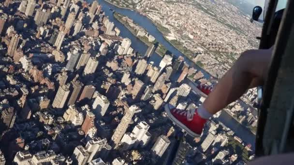 游客的腿和脚在红色高切查克 泰勒的视线中 悬挂在一架直升机上 该直升机白天在纽约市曼哈顿上空飞行 — 图库视频影像