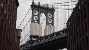 Manhattan Köprüsü 'nün gündüz saatlerinde DUMBO mahallesindeki iki bina arasında çerçevelendiğini gösteren bir video.