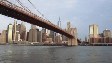 Brooklyn Köprüsü 'nü ve kulesini gündüz vakti New York şehrinin siluetine karşı gösteren bir çekim.