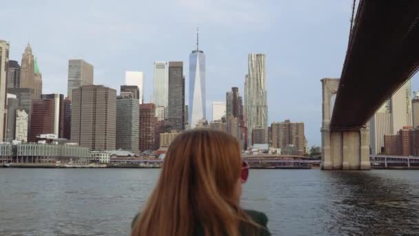 一名身穿绿色外套 戴着红色太阳镜的妇女在布鲁克林大桥附近向右看了看 拍摄了一张倾斜的照片 — 图库视频影像