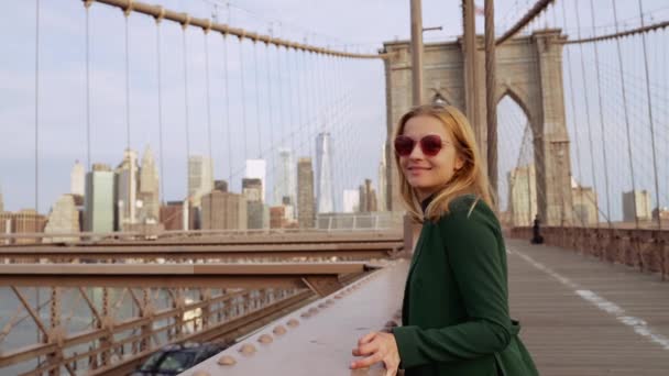 Video Kvinne Grønn Frakk Røde Solbriller Ved Brooklyn Bridge Som – stockvideo