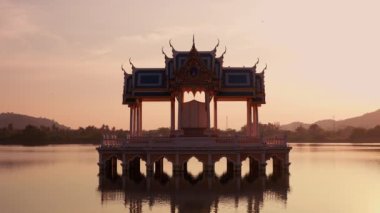 Khao Tao Gölü Tapınağı 'nın geniş açısında. Tayland' da gün batımında tek bir kuş uçuyor ve iki kuş sağ çatıda dinleniyor.