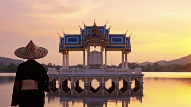 在泰国 一个身穿和服 头戴竹帽的女人看着风景 在日落时走到右边 这幅照片仍然是高渡湖寺庙的照片 — 图库视频影像