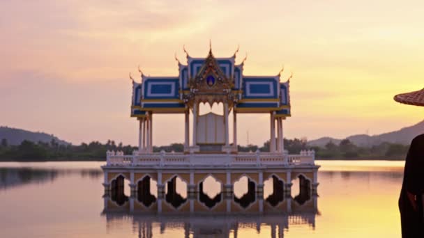 在泰国 高渡湖寺庙仍保留着一张照片 鸟儿四处飞翔 一位女士戴着和服和竹帽 看着它 夕阳西下时离开了现场 — 图库视频影像