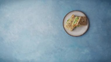 Top view shot of three poke sandwiches being served on a plate on a blue table