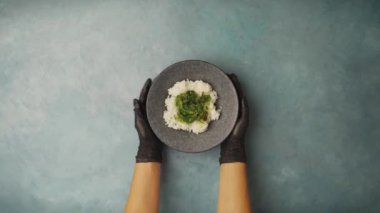 Top view shot of a salmon poke bowl being prepared on a blue table