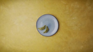 Top view shot of a plate of dumplings topped with sesame seeds and chili sauce while the sauce bowls were filled with soy sauce and mayonnaise