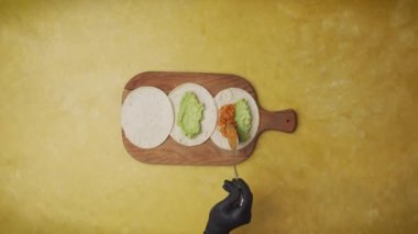 Top view shot of three tortillas with tuna and salmon poke recipes are presented on a plate after being prepared on a yellow table