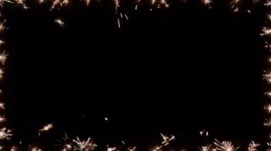 Sparklers burning brightly and flickering on the borders of the frame on a dark background