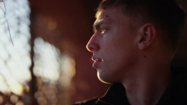 A close-up shot of a man touching the steel mesh fence while looking towards the view of the sunset