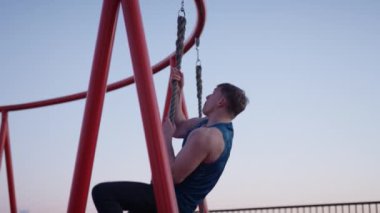 A man doing rope climbing exercise at the rooftop during sunset