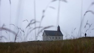 Low angle shot of a man standing still outside Strandarkirkja church in Iceland