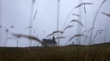 Low angle shot from the ground showing a man standing at a distance outside Strandarkirkja church in Iceland