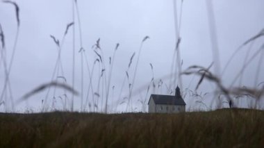 Low-angle long shot of a man standing outside Strandarkirkja church in Iceland