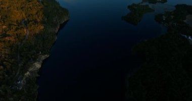A wide drone flight over the Lake District tilting upwards, revealing the snow-capped Tronador mountain at Bariloche, Argentina during dawn