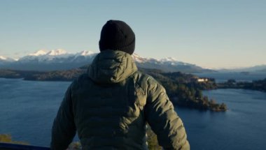 An arc shot of a man sightseeing and appreciating the view of Nahuel Huapi lake at Bariloche, Argentina