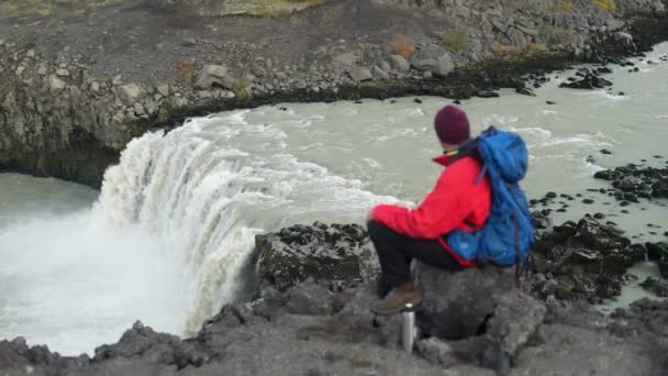 大きな岩の上に座っている間にThjofafoss滝を観察男の左側の角度から撮影されたビデオ映像 — ストック動画