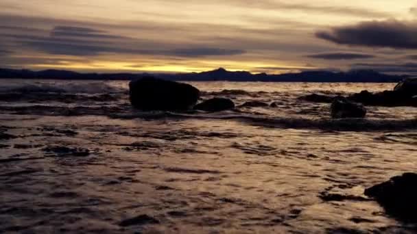 在日出的时候 在阿根廷巴里洛切的一个湖边 岩石和山脉的轮廓依然清晰如画 岩石上洒满了水 — 图库视频影像