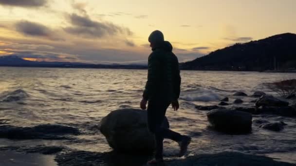 Wide Shot Showing Back View Man Walking Lakeshore Large Rocks — Vídeo de stock