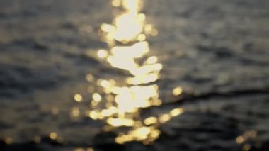 Arjantin 'in Bariloche kentindeki bir göle yansıyan Bokeh güneş doğumu efektiyle akan dalgaların bulanık görüntüsü.