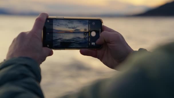 在阿根廷巴里洛切拍摄的一张显示一名男子双手的手机闪烁的特写照片 拍摄了日出期间海浪的照片 — 图库视频影像