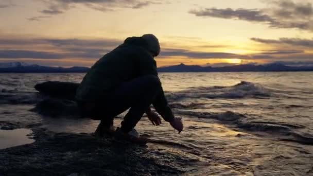 在阿根廷巴里洛切 一名男子在日出时用岩石湖滨上的水洗脸的轮廓 — 图库视频影像
