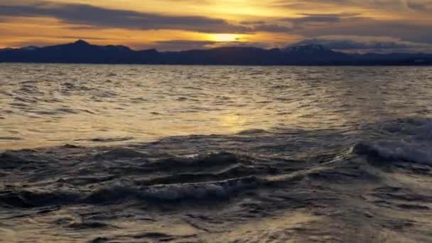 日の出の間にアルゼンチンのバリローチェに流れる山脈と波のシルエットの静止したショット — ストック動画
