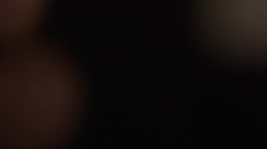 A close-up shot of a blurry horizontal burning matchstick that slowly goes into focus against a dark background