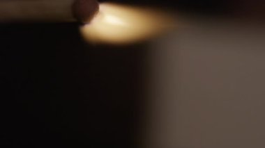 A close-up shot of a blurry burning matchstick that slowly goes into focus against a blurred background